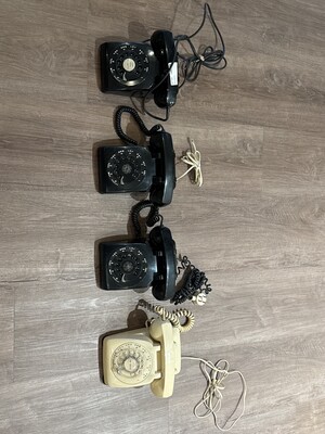 Grouping of four vintage rotary telephones arranged on a plain wooden