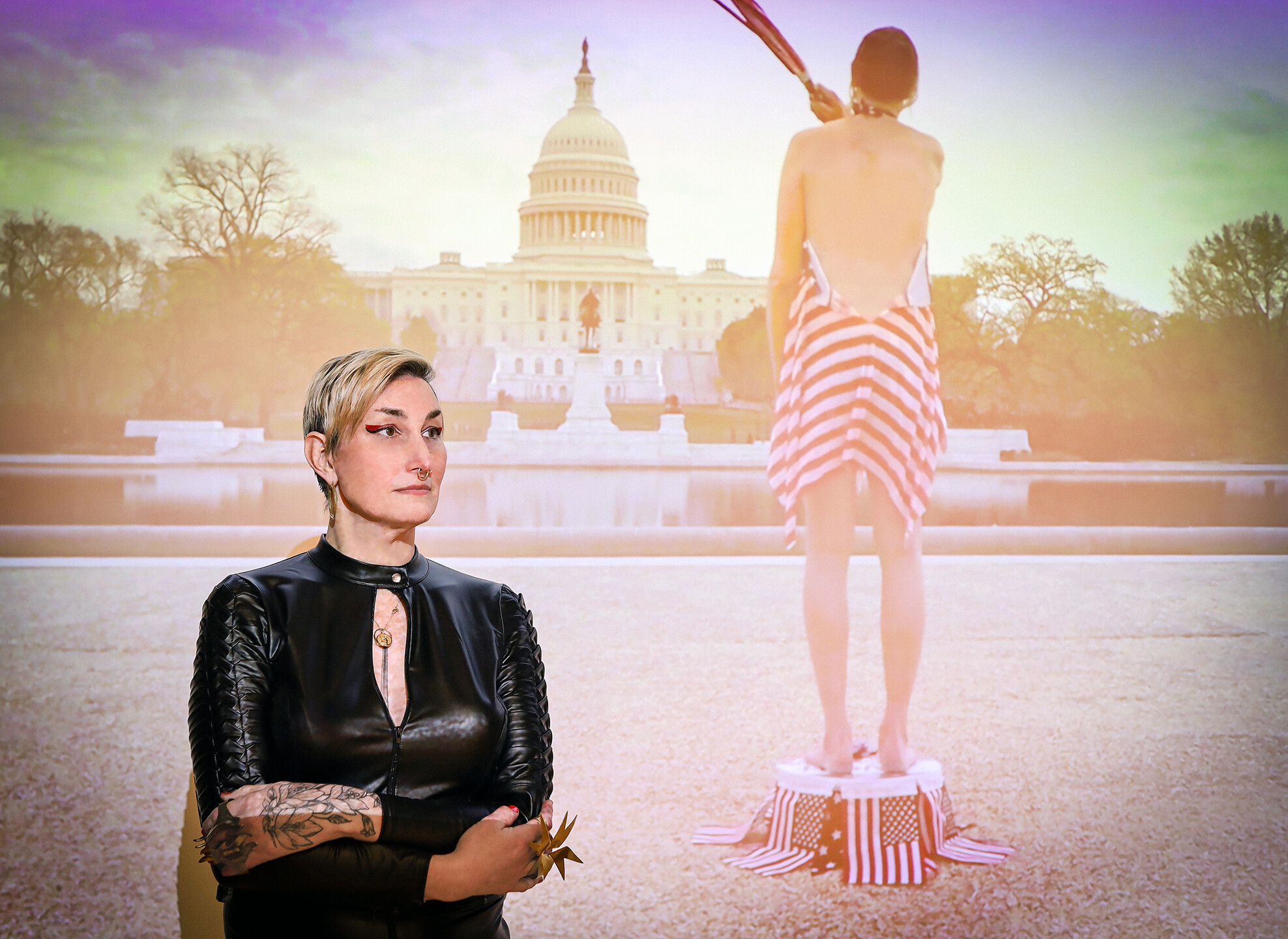 Vaughan stands for a photograph in front of the video projection of Atonement for Imaginary Sins, performed in Washington D.C. IMAGE BY KELLY O.