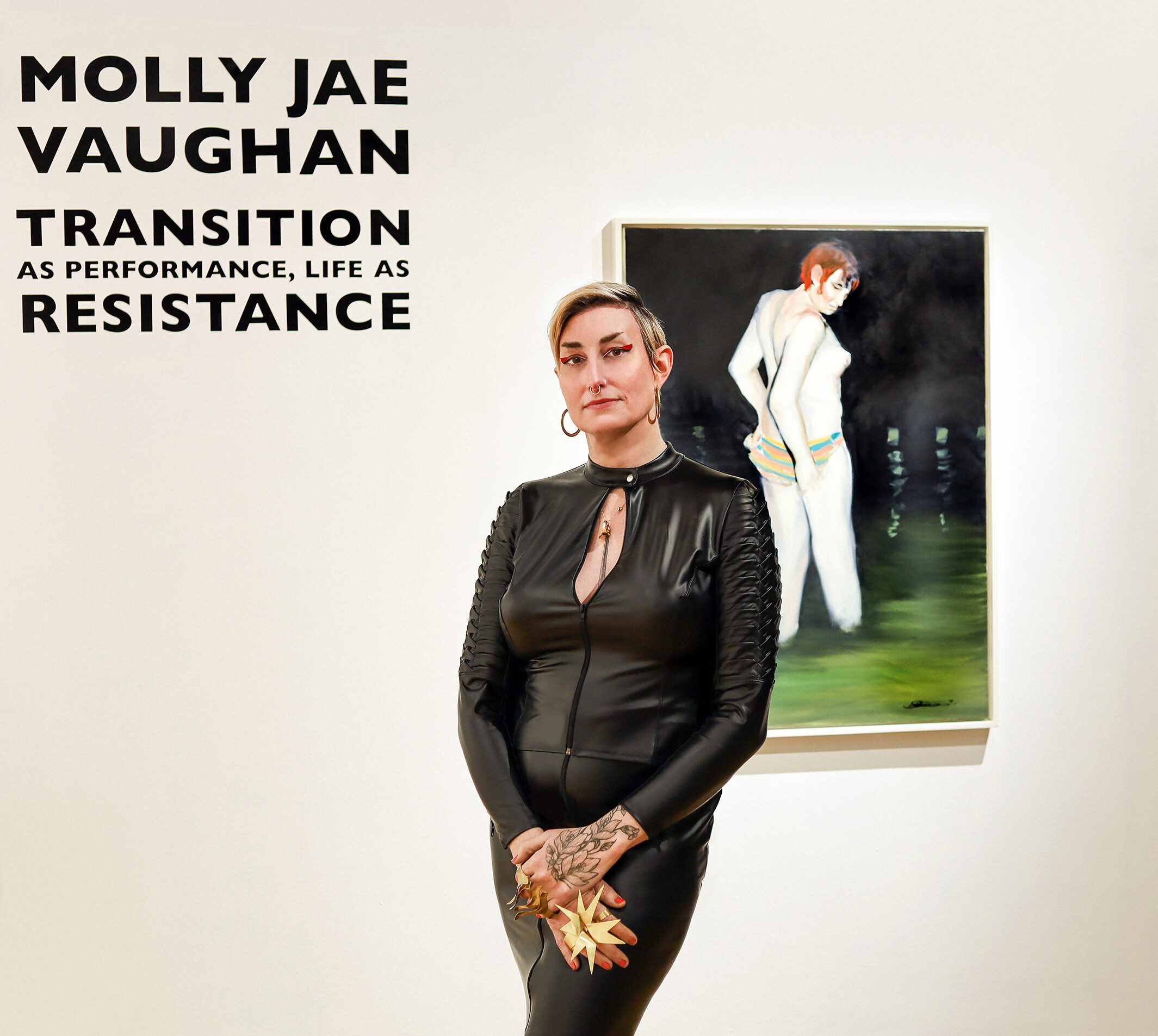 Vaughan poses in front of her painting, Fixing My Suit, at Hedreen Gallery. This painting marks the beginning of a series of oil paintings in the exhibition that explore her transsexual identity and body.